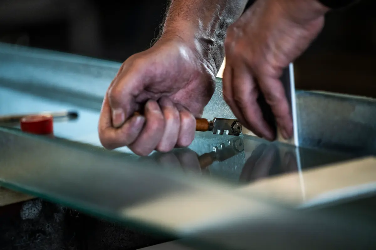 Handwerker schneidet Glas mit Glasschneider für Glasbau-Konstruktionen